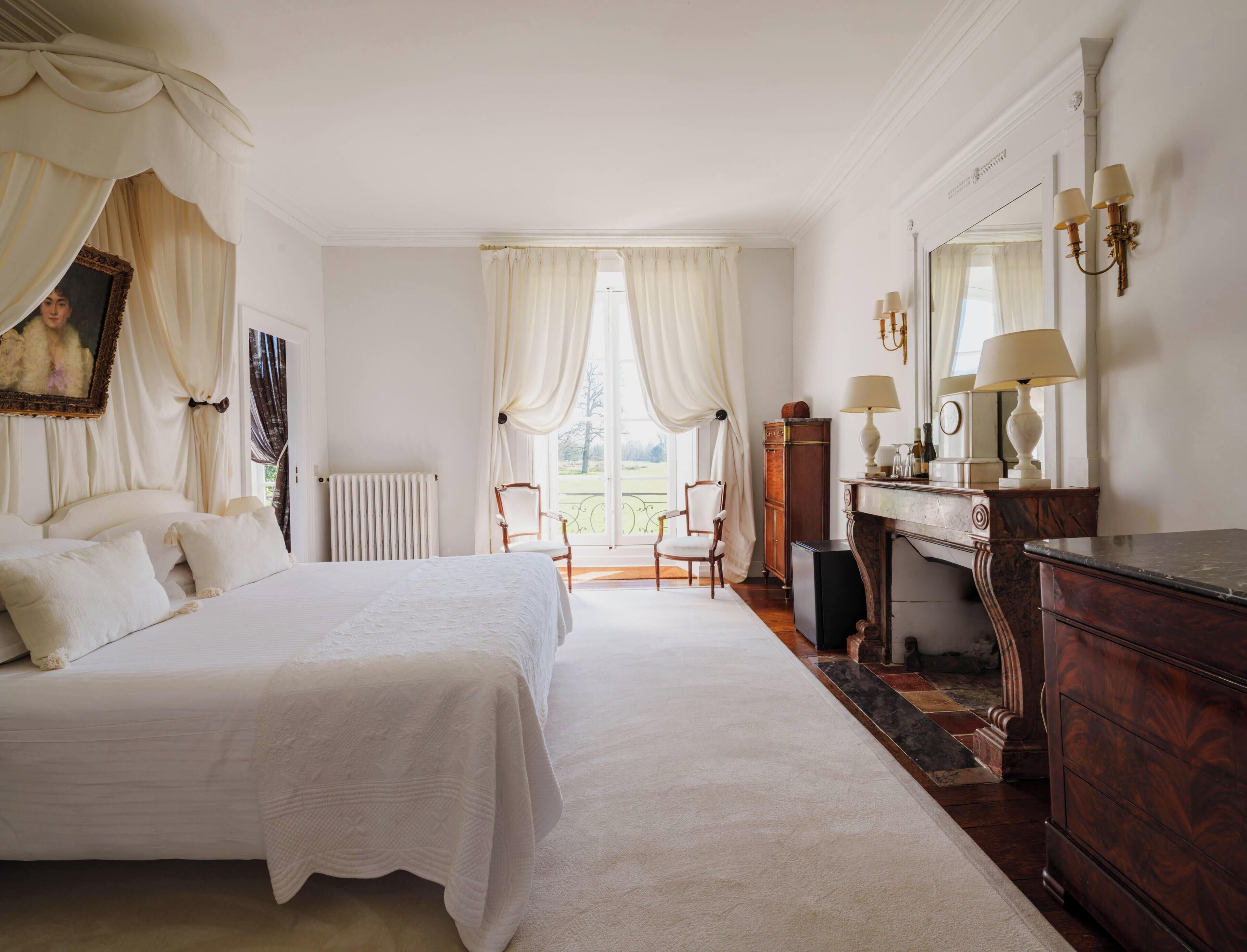 Quarto com uma cama grande, cômoda, cadeira, radiador e vista para o exterior.