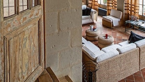 A rustic room with a wooden door, stone walls, and a cozy seating area with a sofa and chairs.