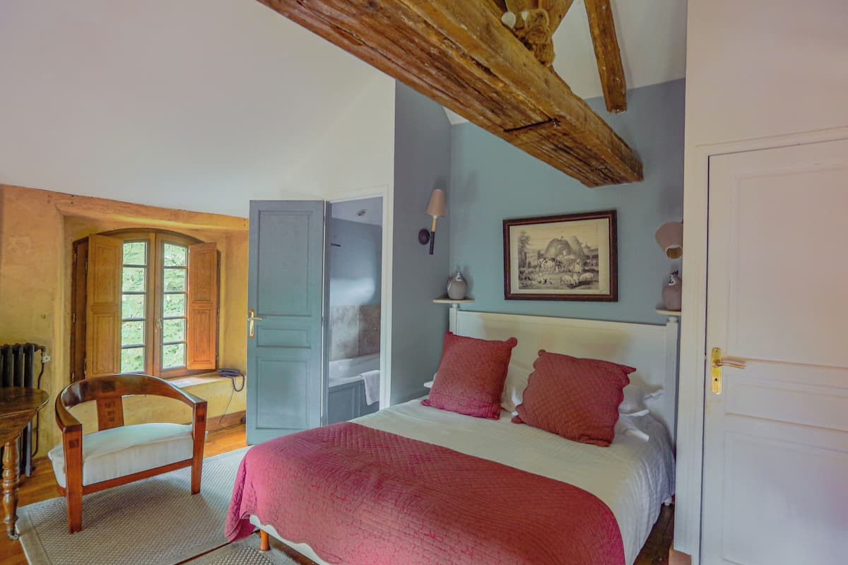 Un dormitorio con cama, una silla, armario y puerta.