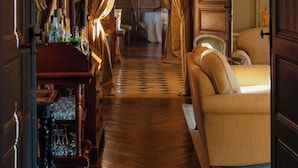 A room with a wooden floor, a sofa, a cabinet, and a bar area with bottles and glasses.