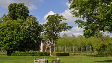 A stone building with an arched entrance, surrounded by a well-manicured lawn and tall trees.