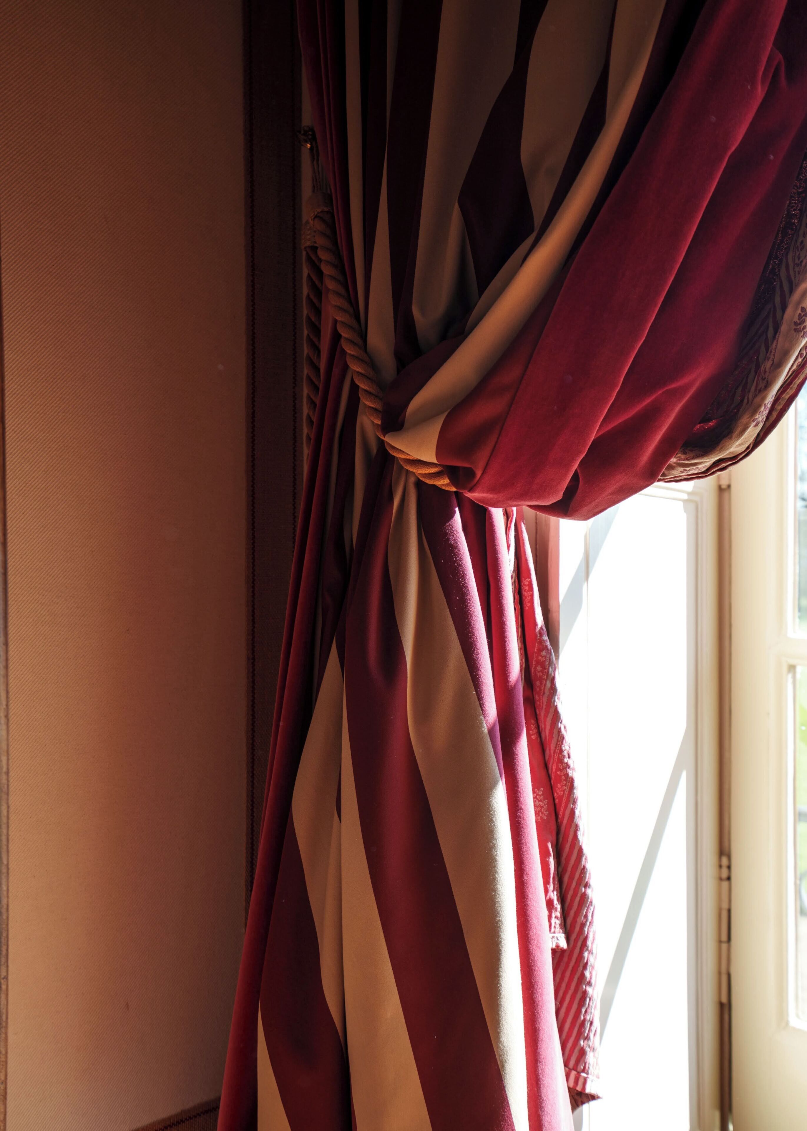 A curtain tied in a knot, a window, and a wall.