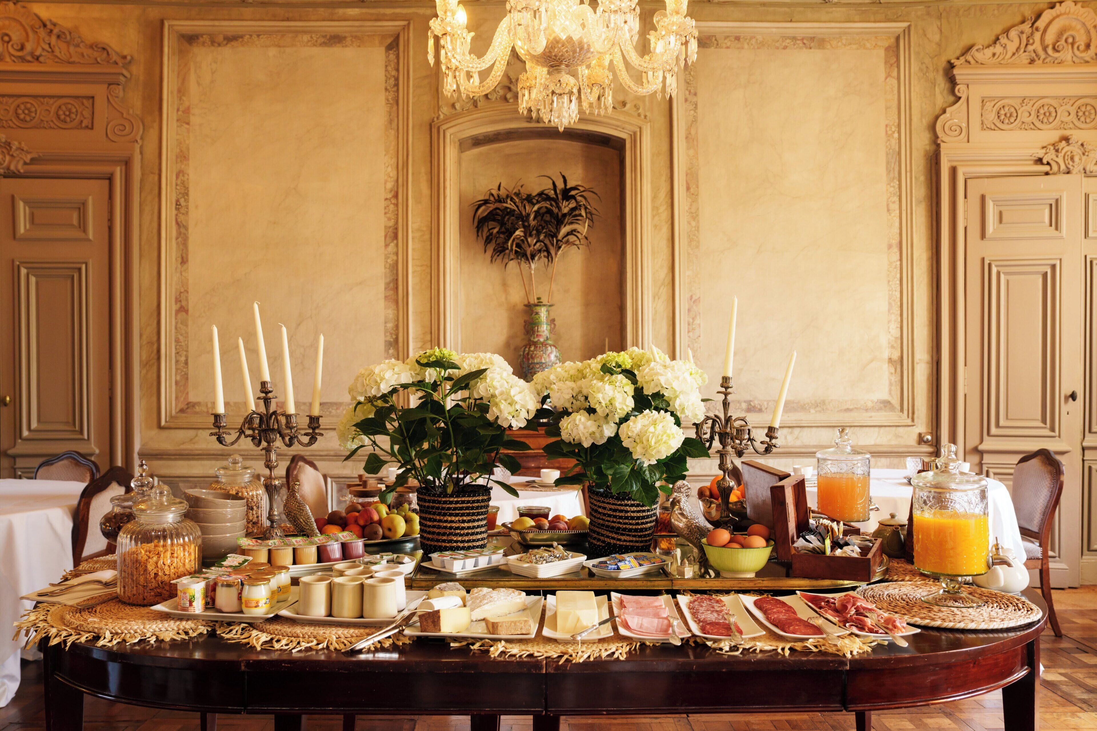 A breakfast buffet with various food items, a chandelier, and ornate wall decorations.