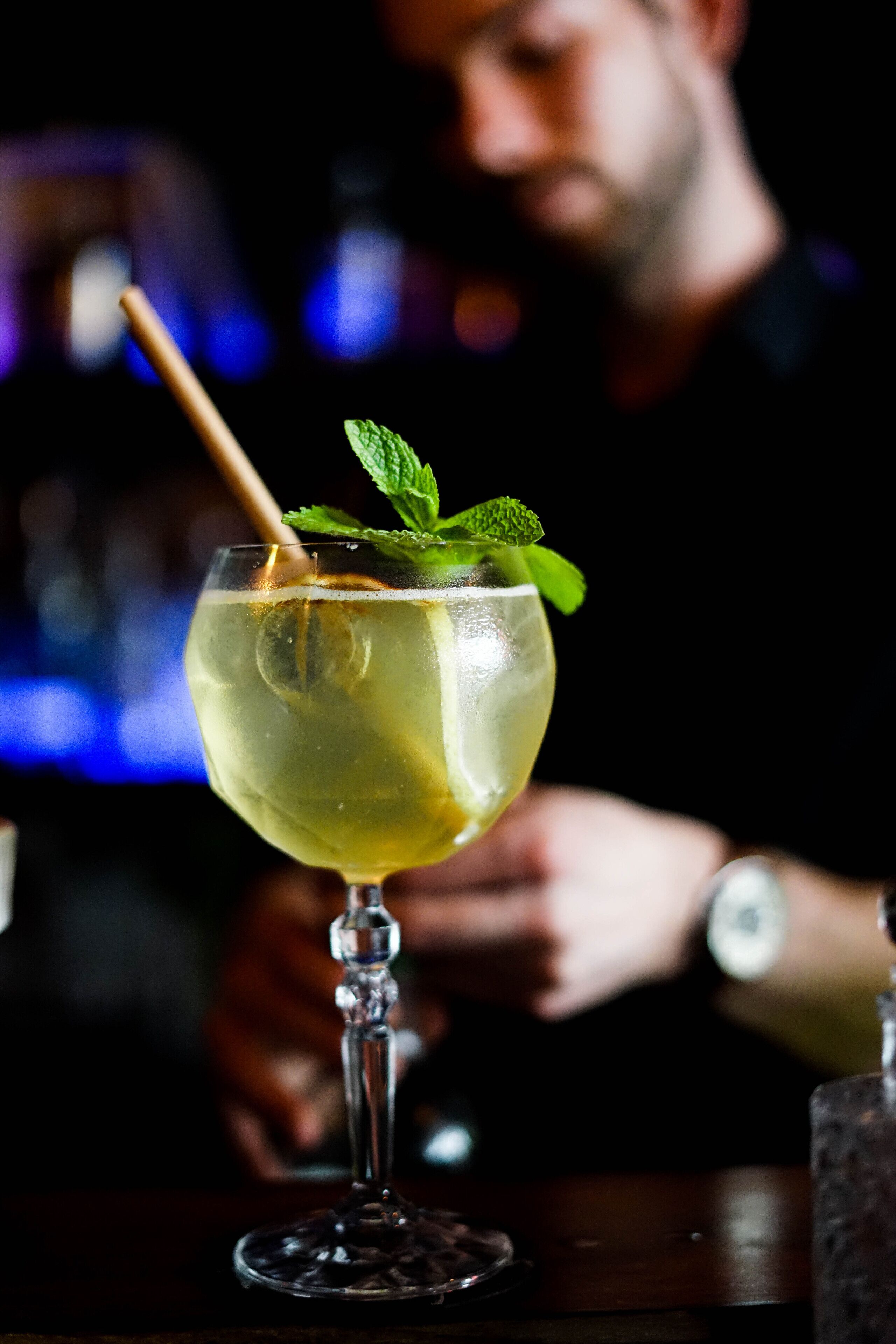 A cocktail glass with a mint garnish on a bar counter.