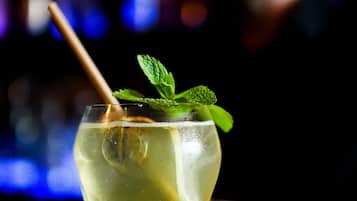 A cocktail glass with a mint garnish on a bar counter.