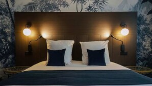 Cama com duas almofadas brancas e um cobertor azul escuro.