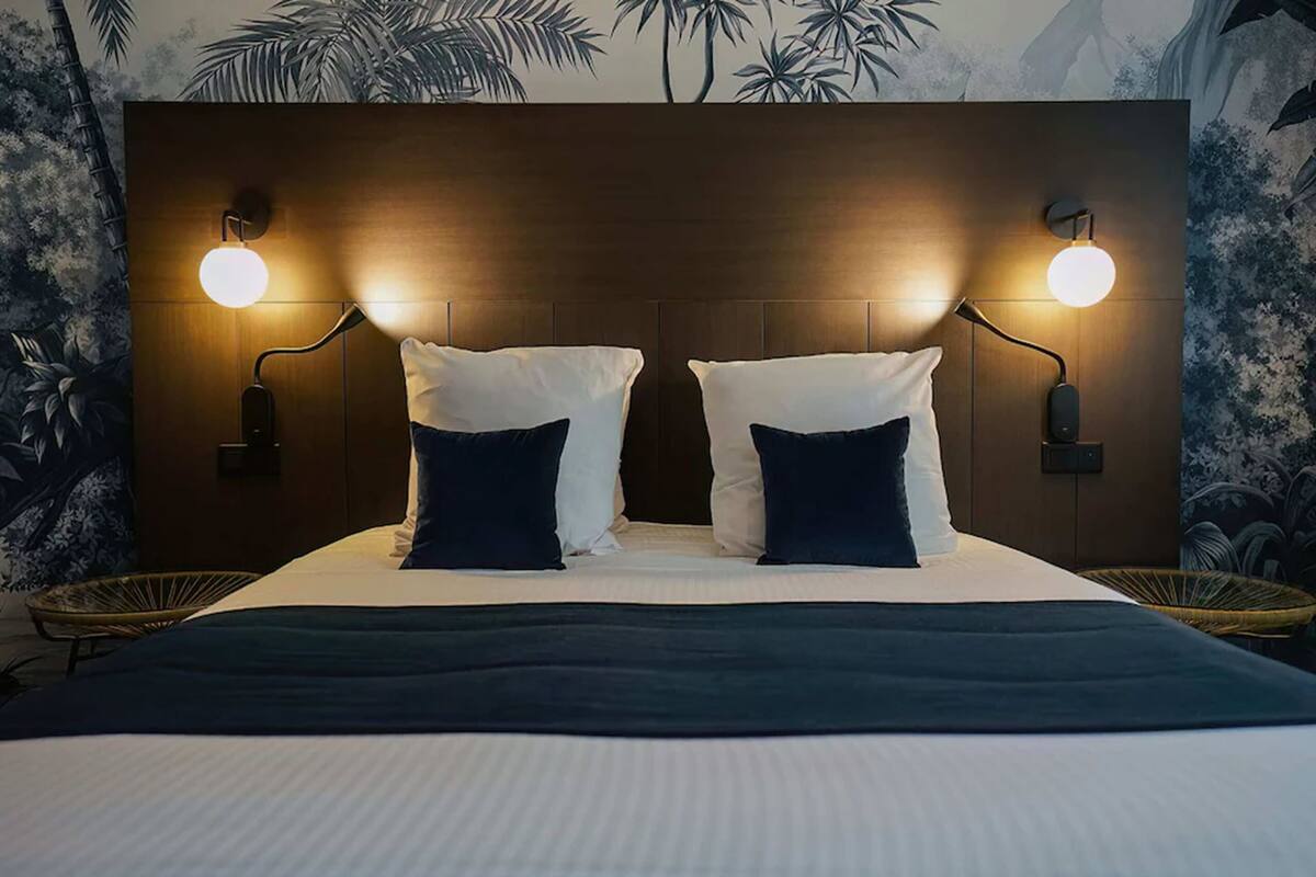 A bed with two white pillows and a dark blue throw blanket.