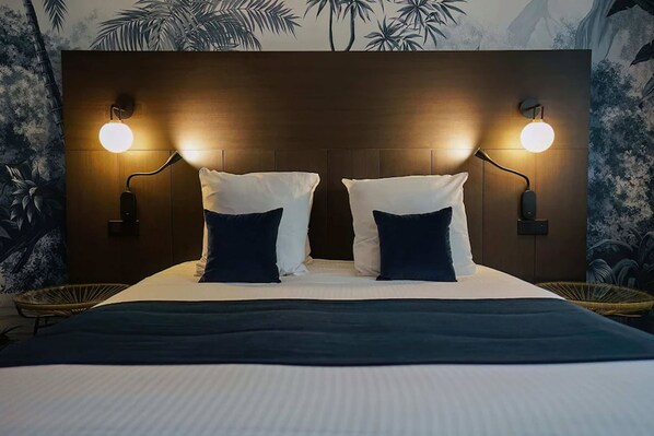 Una cama con dos almohadas blancas y un edredón azul oscuro.