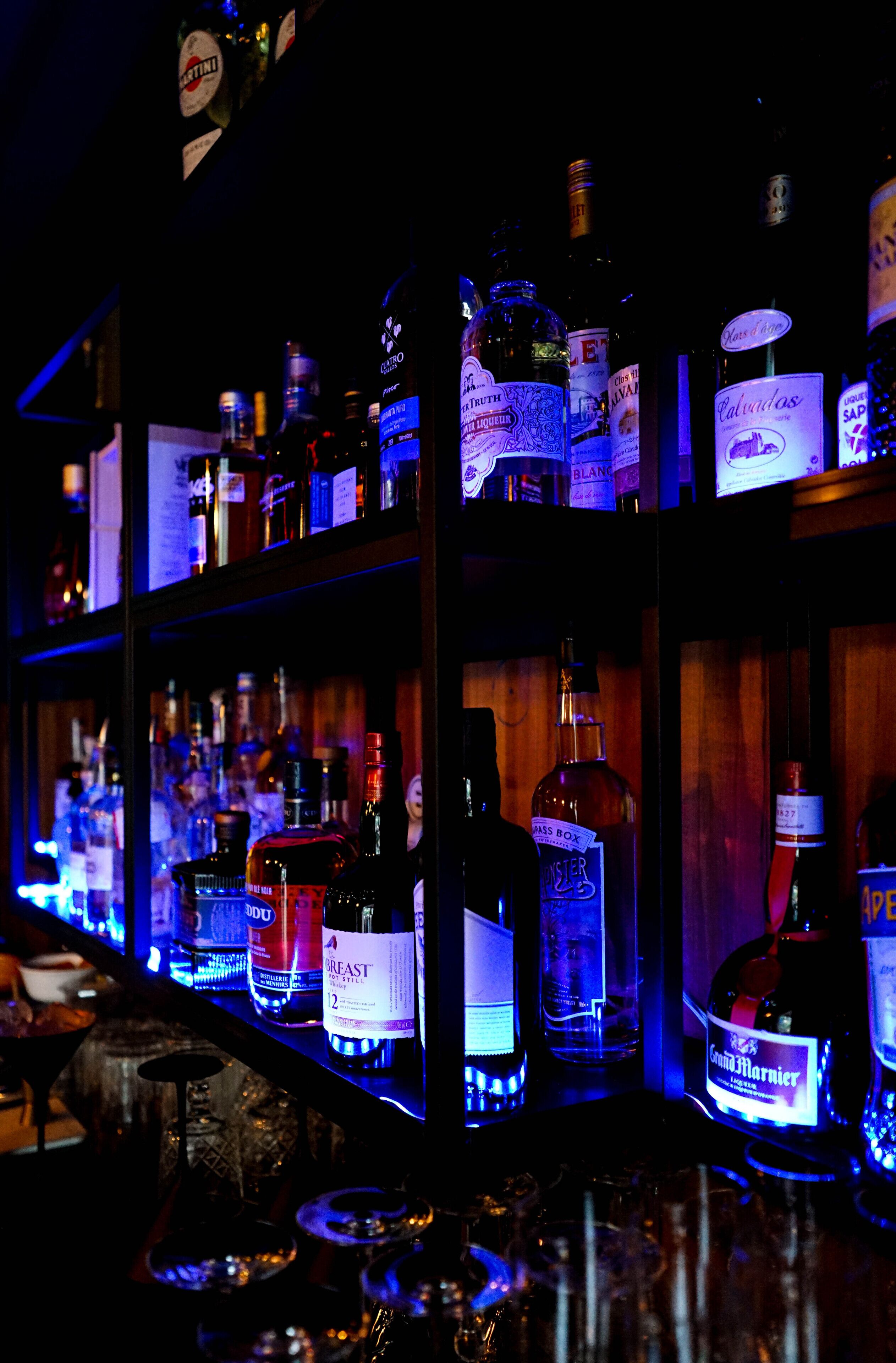 Un bar dont les étagères sont remplies de différentes bouteilles d’alcool.