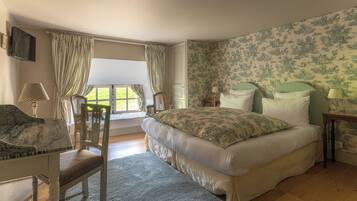 A bedroom with a bed, a chair, a desk, and a window.
