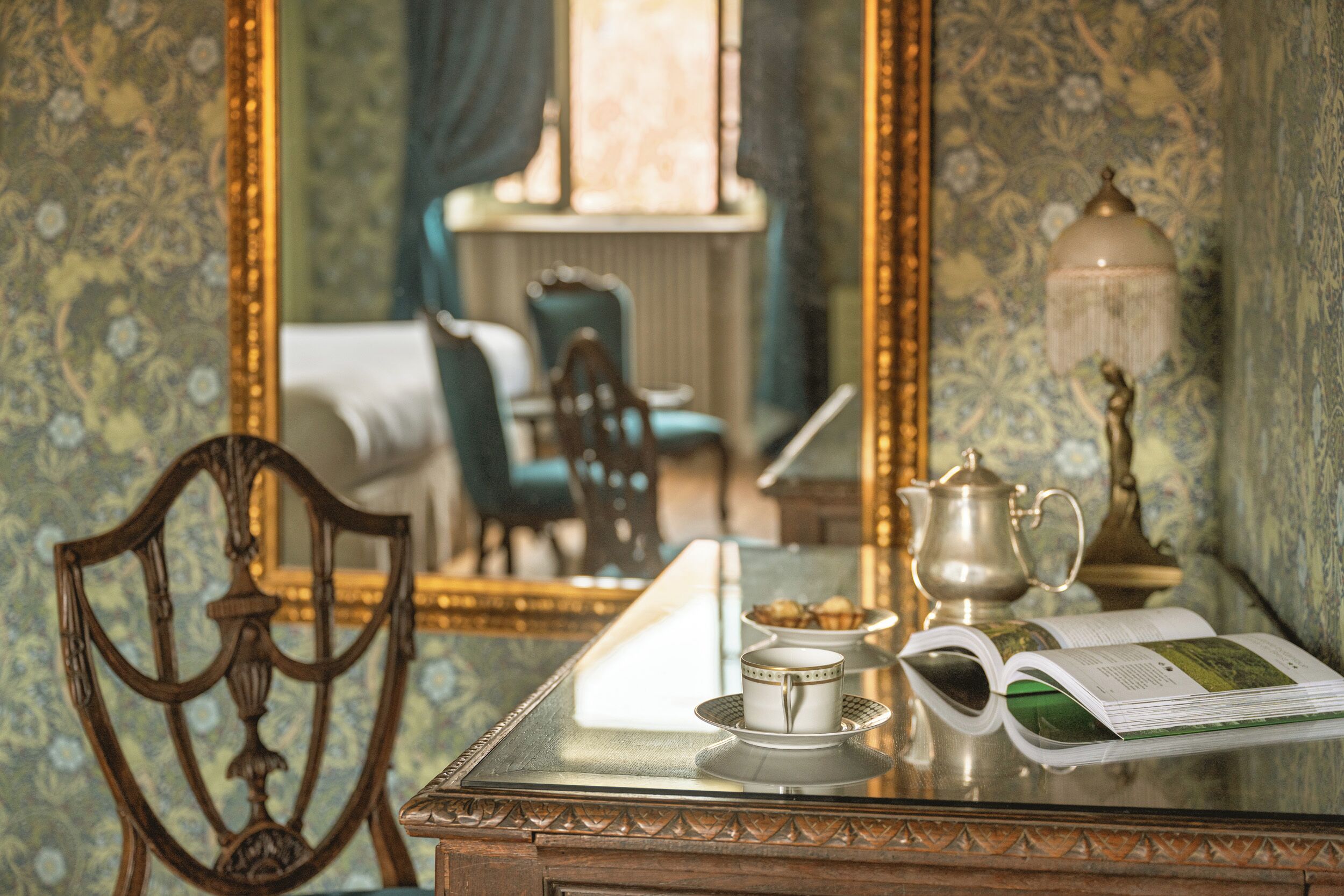 Une pièce comprenant une table en verre, une chaise, un lit, une lampe et un miroir.