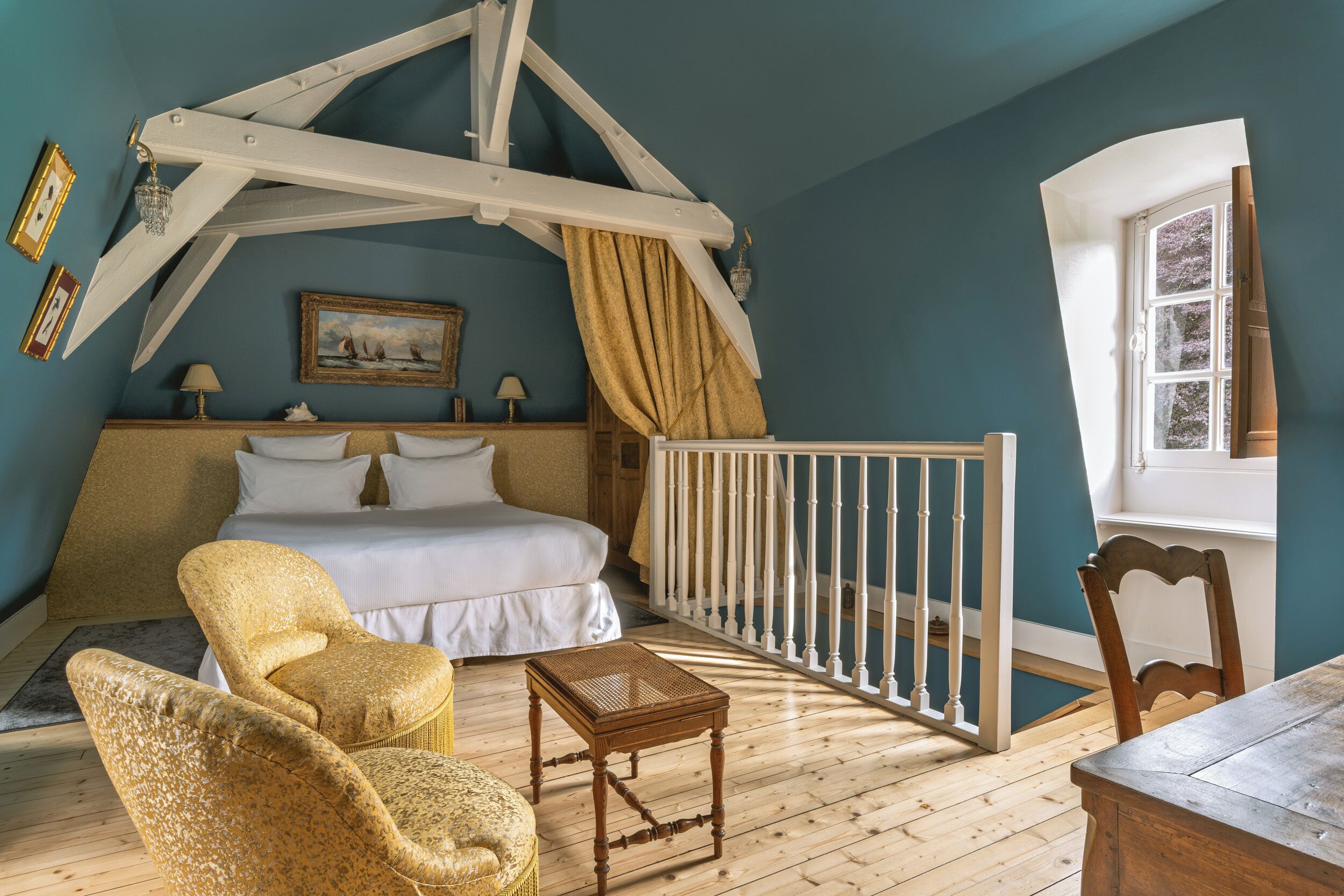 Een slaapkamer met een bed, een stoel, een klein tafeltje, een wieg en een raam.