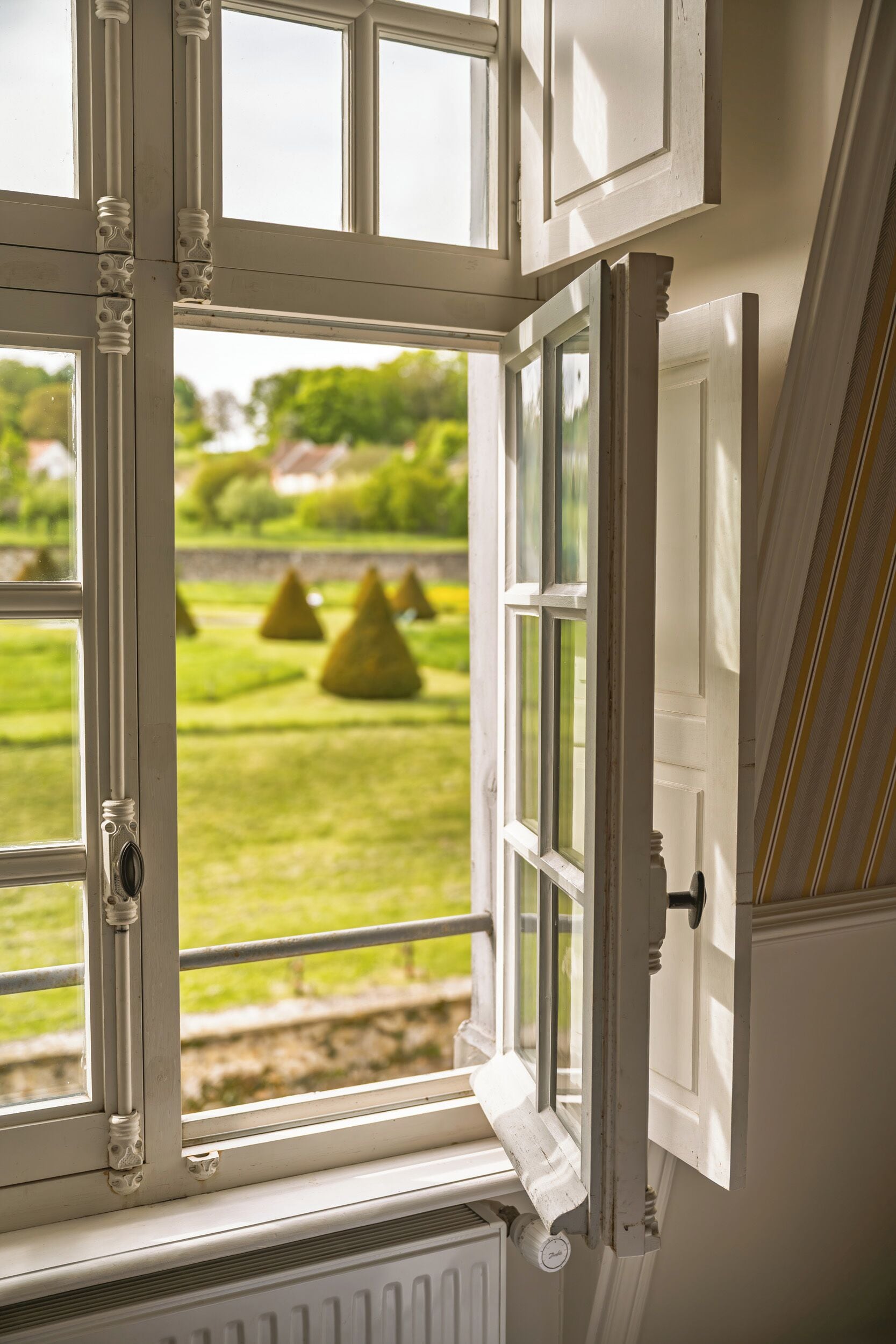 A window with a view of a green lawn and trees.