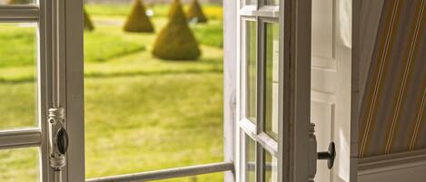 A window with a view of a green lawn and trees.