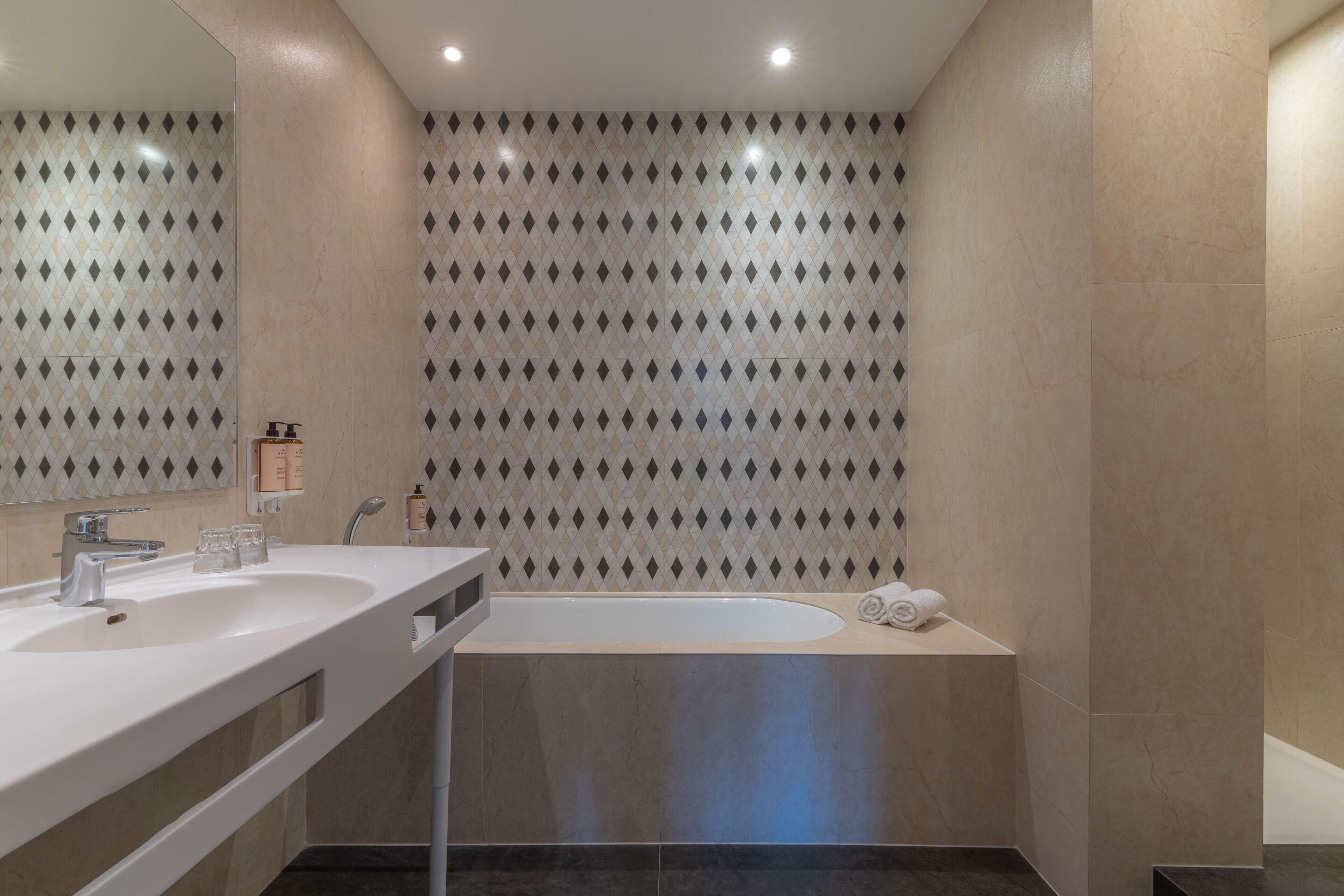 A modern bathroom with two sinks, a bathtub, and a shower.