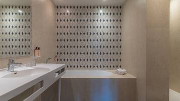 A modern bathroom with two sinks, a bathtub, and a shower.