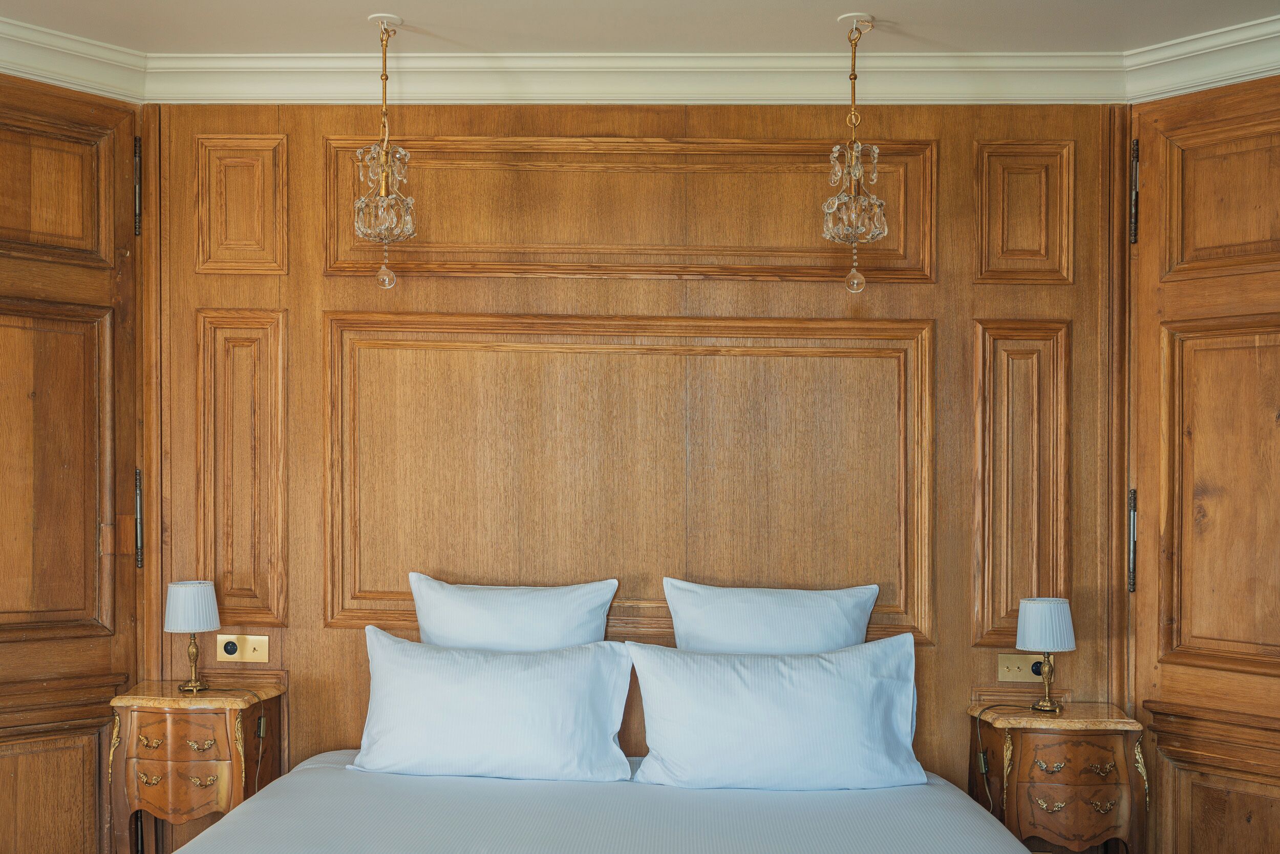 A room with a large bed, wooden paneling, and two nightstands with lamps.