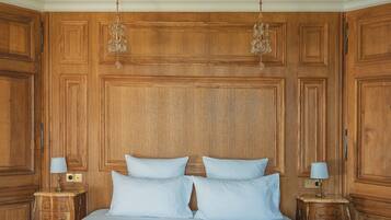 A room with a large bed, wooden paneling, and two nightstands with lamps.