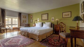 A spacious bedroom with a large bed, wooden furniture, and a view of the outdoors through a window.