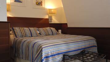 A neatly made bed with striped bedding, a bedside lamp, and two framed artworks on the wall.