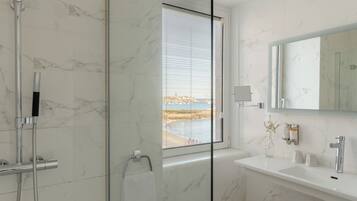 A modern bathroom with a glass shower enclosure, a white marble vanity, and a large mirror.