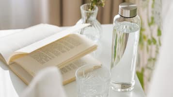 A white table with a book, a clear glass, and a water bottle.