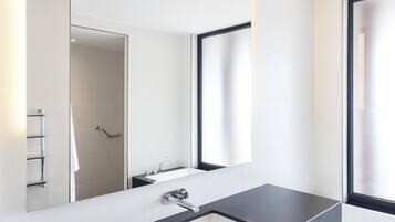 Une salle de bain moderne avec un grand miroir, un plan de toilette noir, un lavabo et une fenêtre.
