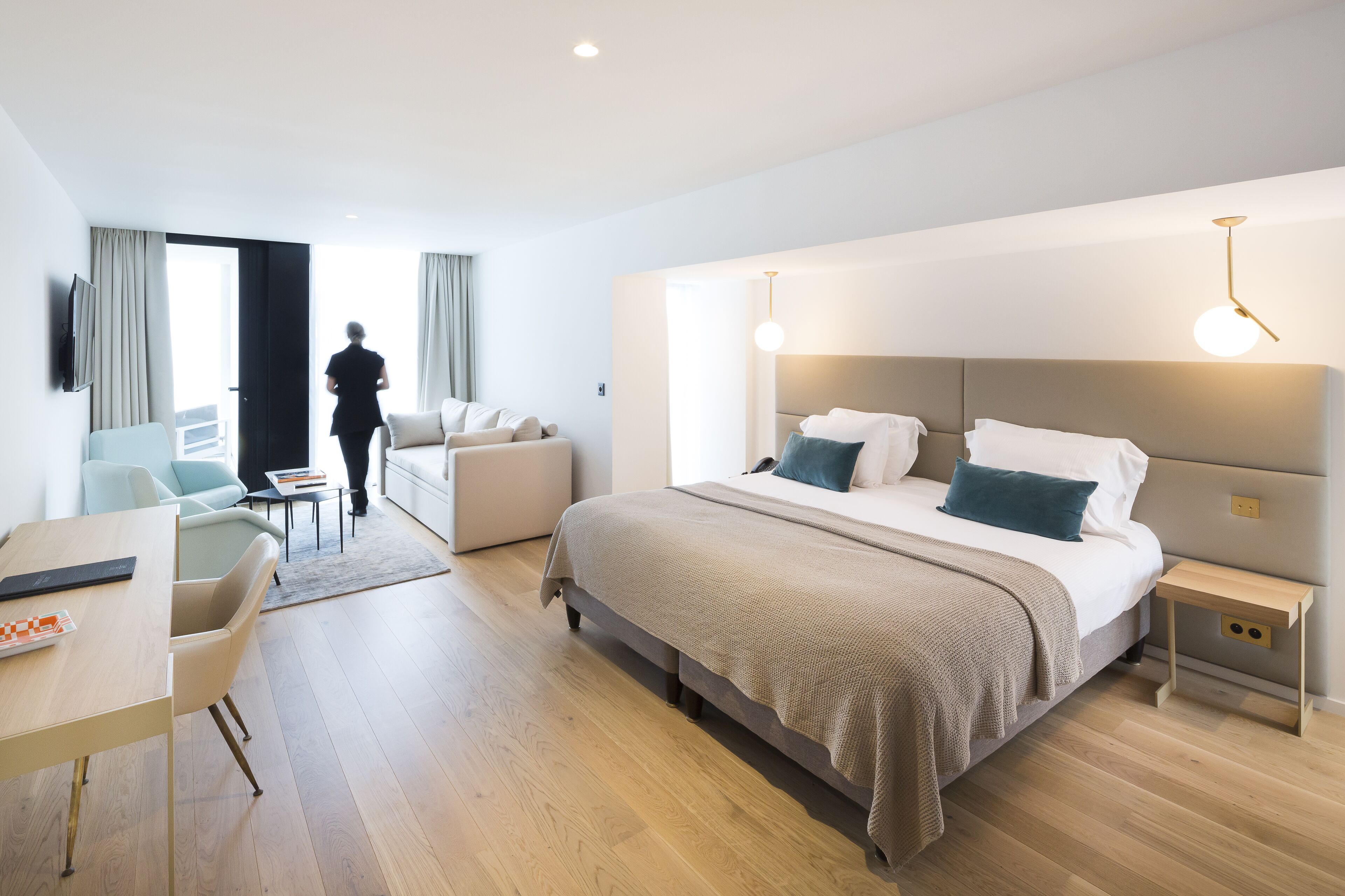 Moderni hotellihuone, jossa on suuri sänky, työpöytä ja oleskelualue.