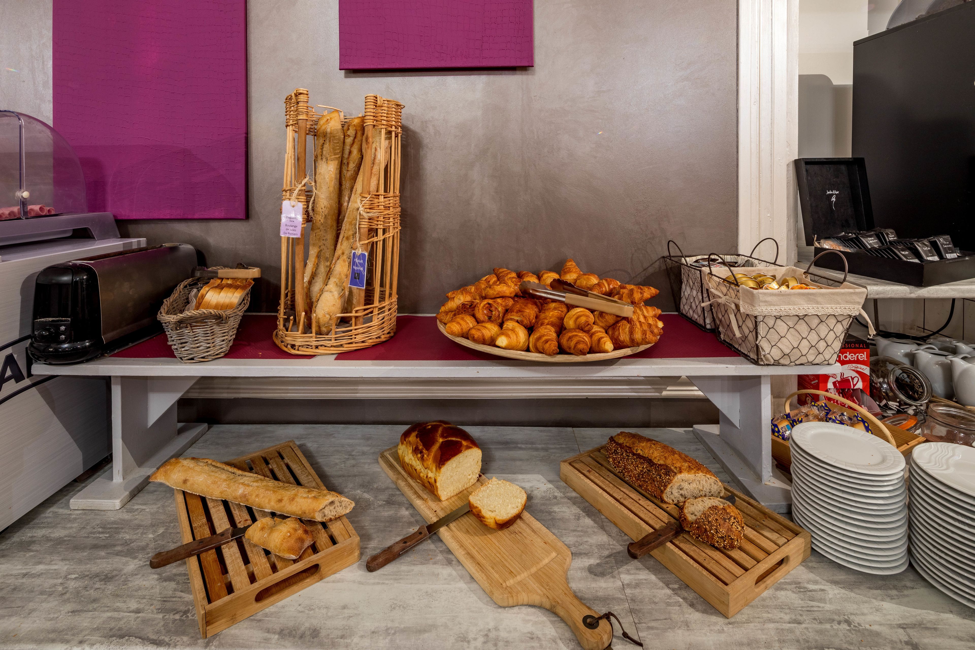 A bakery display with various breads and pastries, including baguettes, croissants, and a loaf of bread on a cutting board.