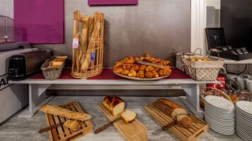 A bakery display with various breads and pastries, including baguettes, croissants, and a loaf of bread on a cutting board.