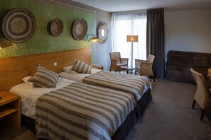 Een hotelkamer met twee bedden, een houten hoofdbord, een groen structuurwand en een groot raam met gordijnen.