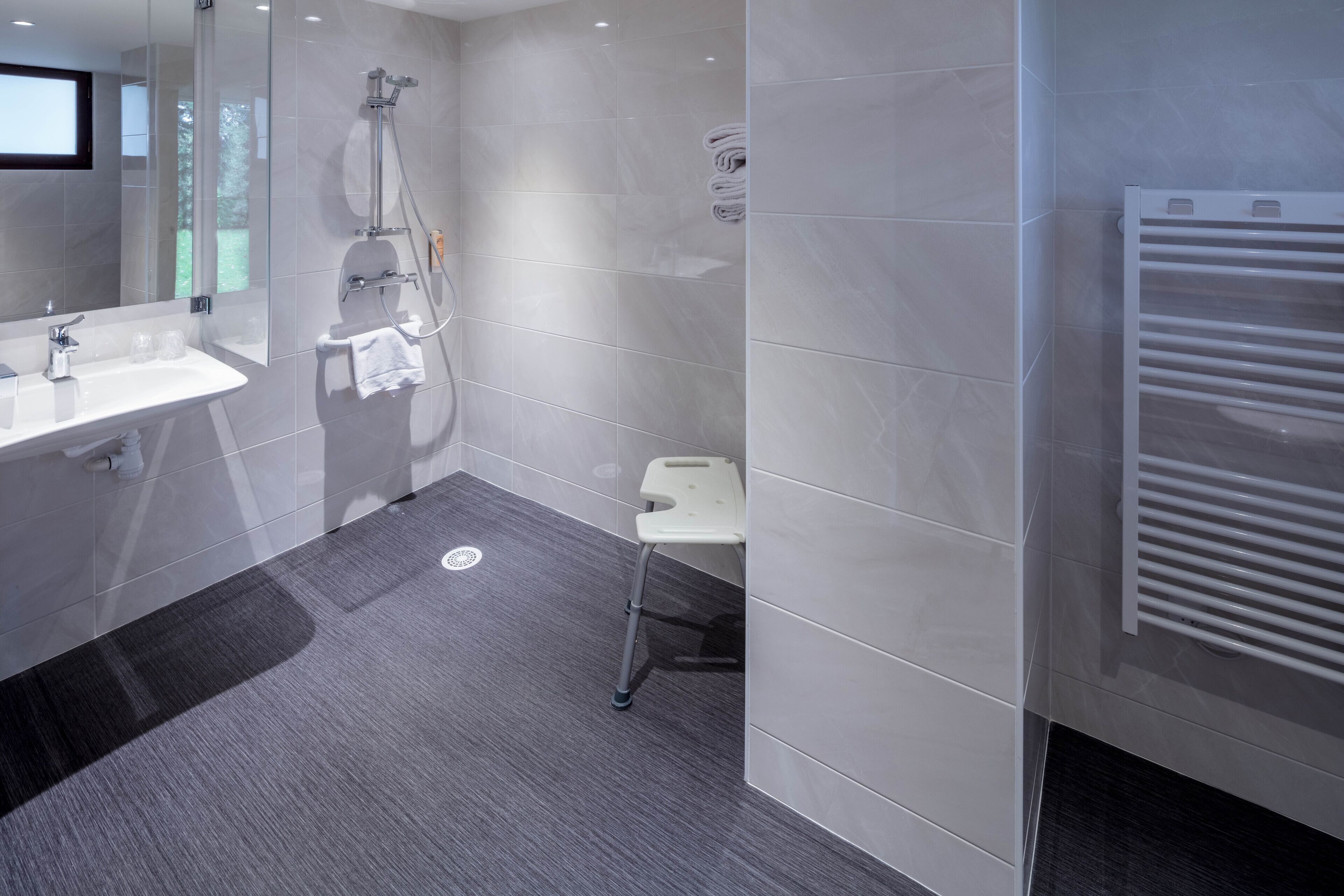 Un bagno moderno con box doccia in vetro, lavandino bianco e porta asciugamani.