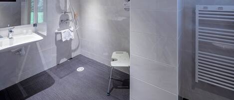 Un bagno moderno con box doccia in vetro, lavandino bianco e porta asciugamani.