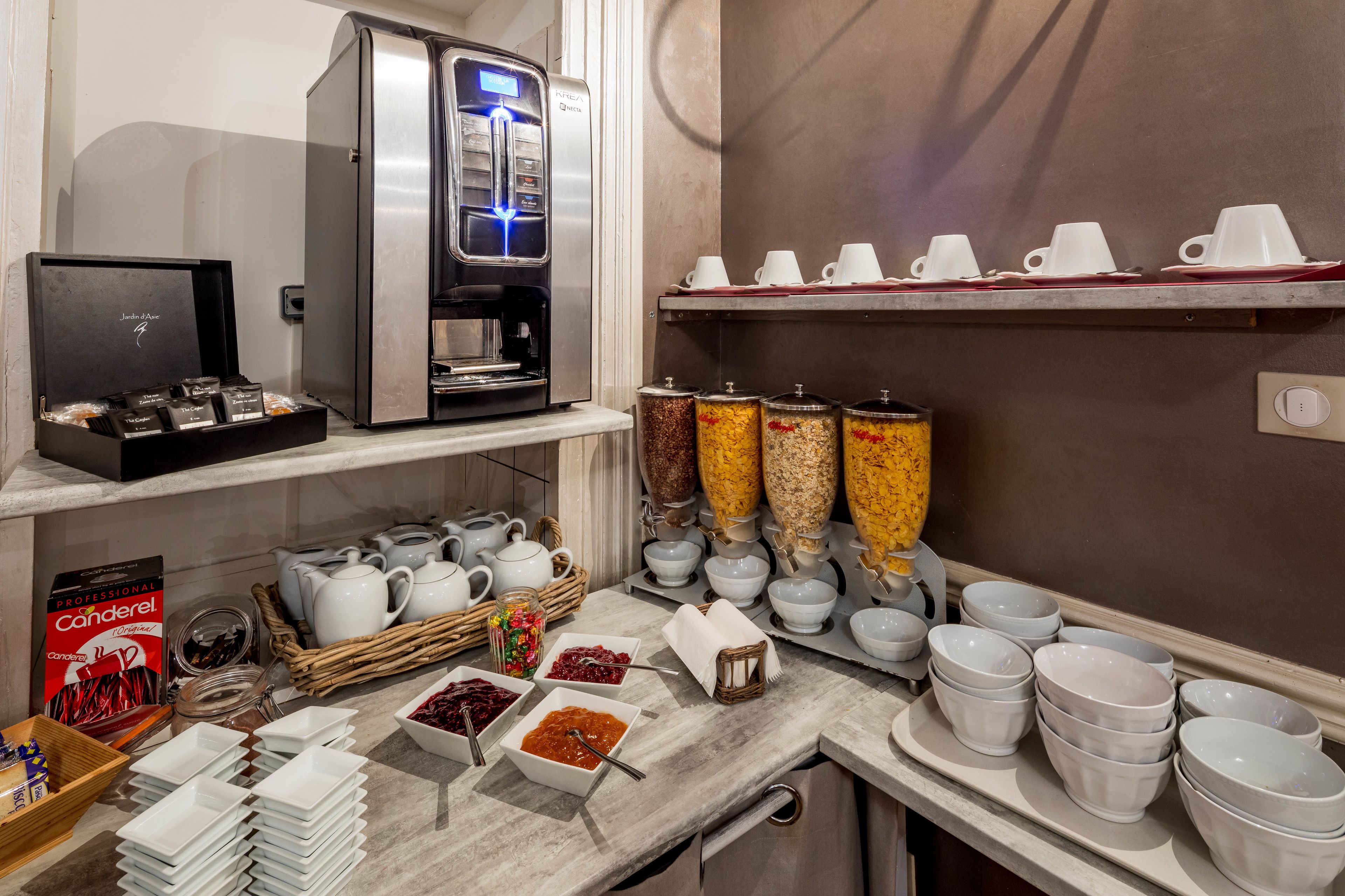 A hotel breakfast area with a coffee machine, tea station, and various breakfast items.