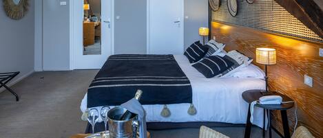 A hotel room with a bed, a dining table with a tray of snacks, a metal pitcher, and a lamp.