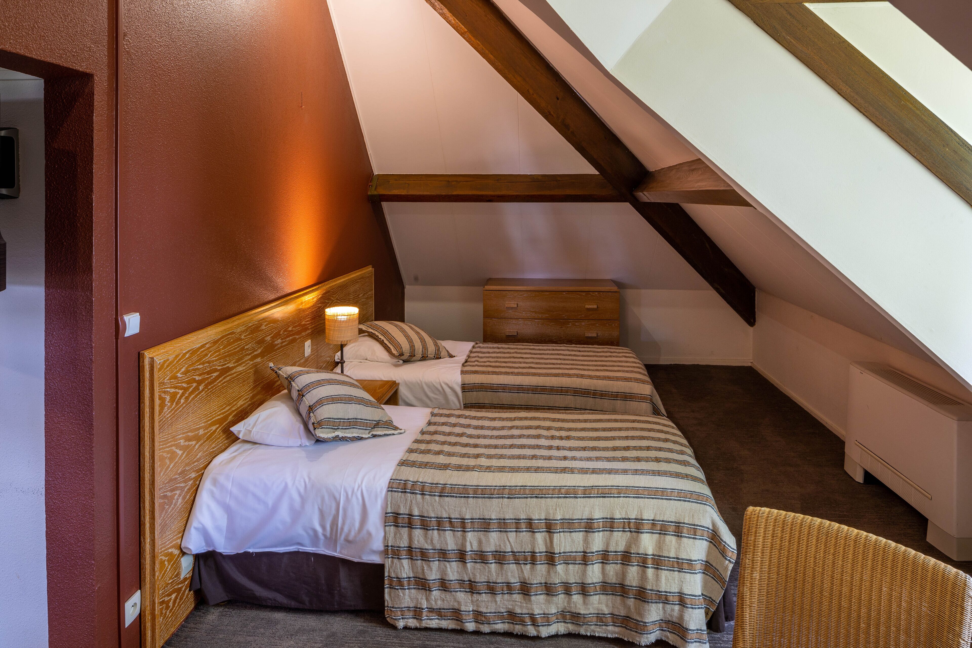 A bedroom with two beds, a wooden headboard, a nightstand, and a chair.