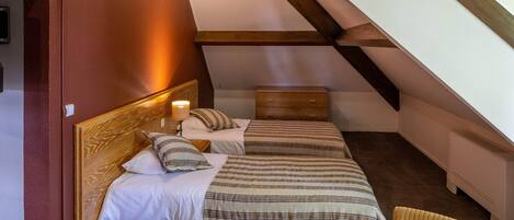A bedroom with two beds, a wooden headboard, a nightstand, and a chair.