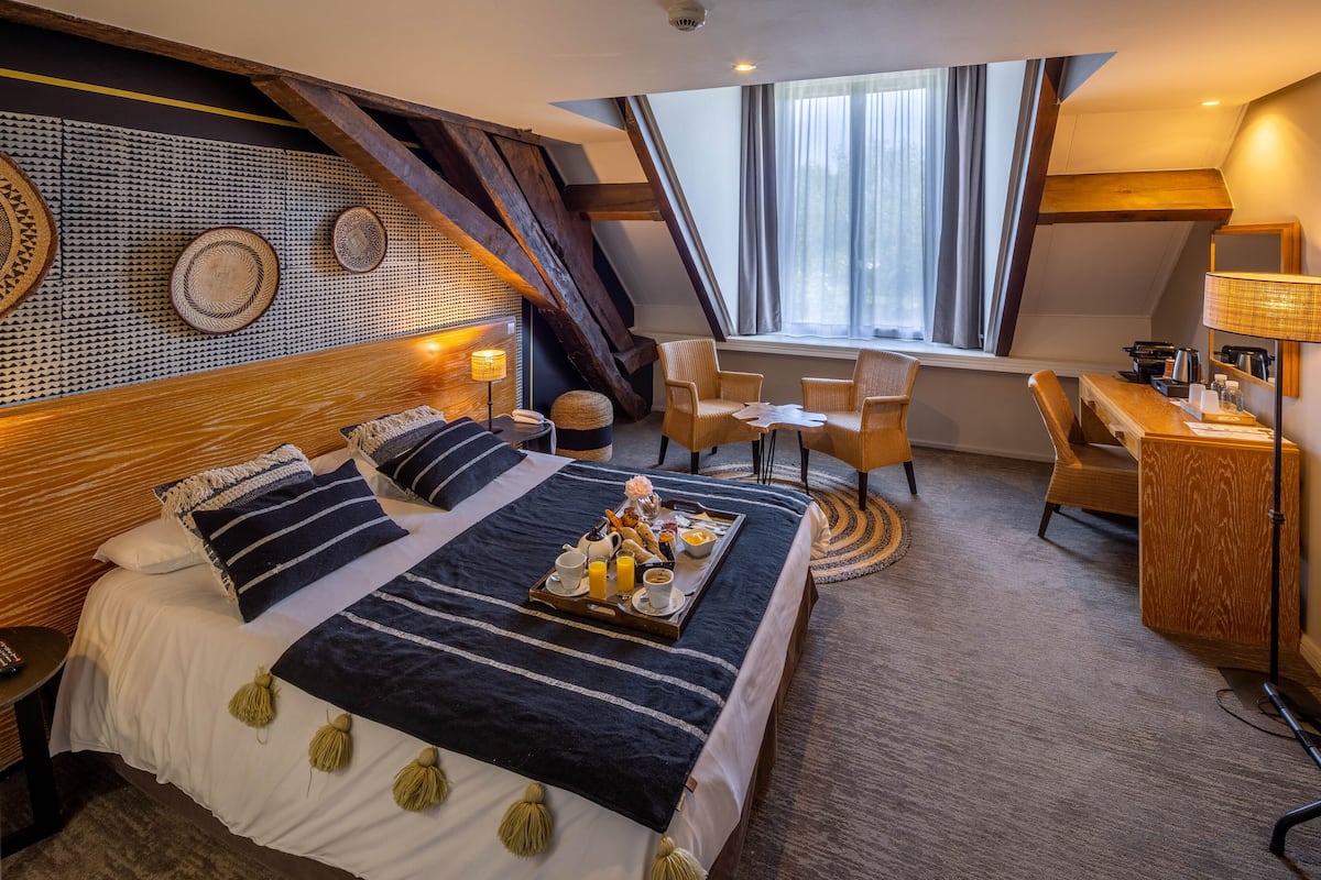 Une chambre d’hôtel avec un grand lit, un bureau, une chaise et une fenêtre avec des rideaux.