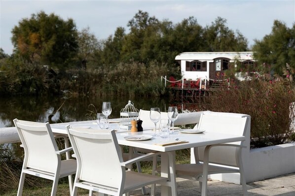 A table set for four with white chairs, a white table, and a white building in the background.