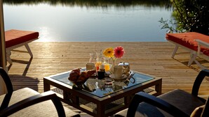 A breakfast setup on a wooden deck with a view of a calm lake. - L'estelle en Camargue (Saintes-Maries-de-la-Mer)