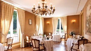 A dining room with multiple tables set for service, elegant chandeliers, and classic wooden chairs. - Château Des Bondons EI (La Ferte-sous-Jouarre)