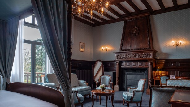 A room with a large bed, multiple armchairs, a fireplace, and a chandelier. - Château Des Bondons EI (La Ferte-sous-Jouarre)