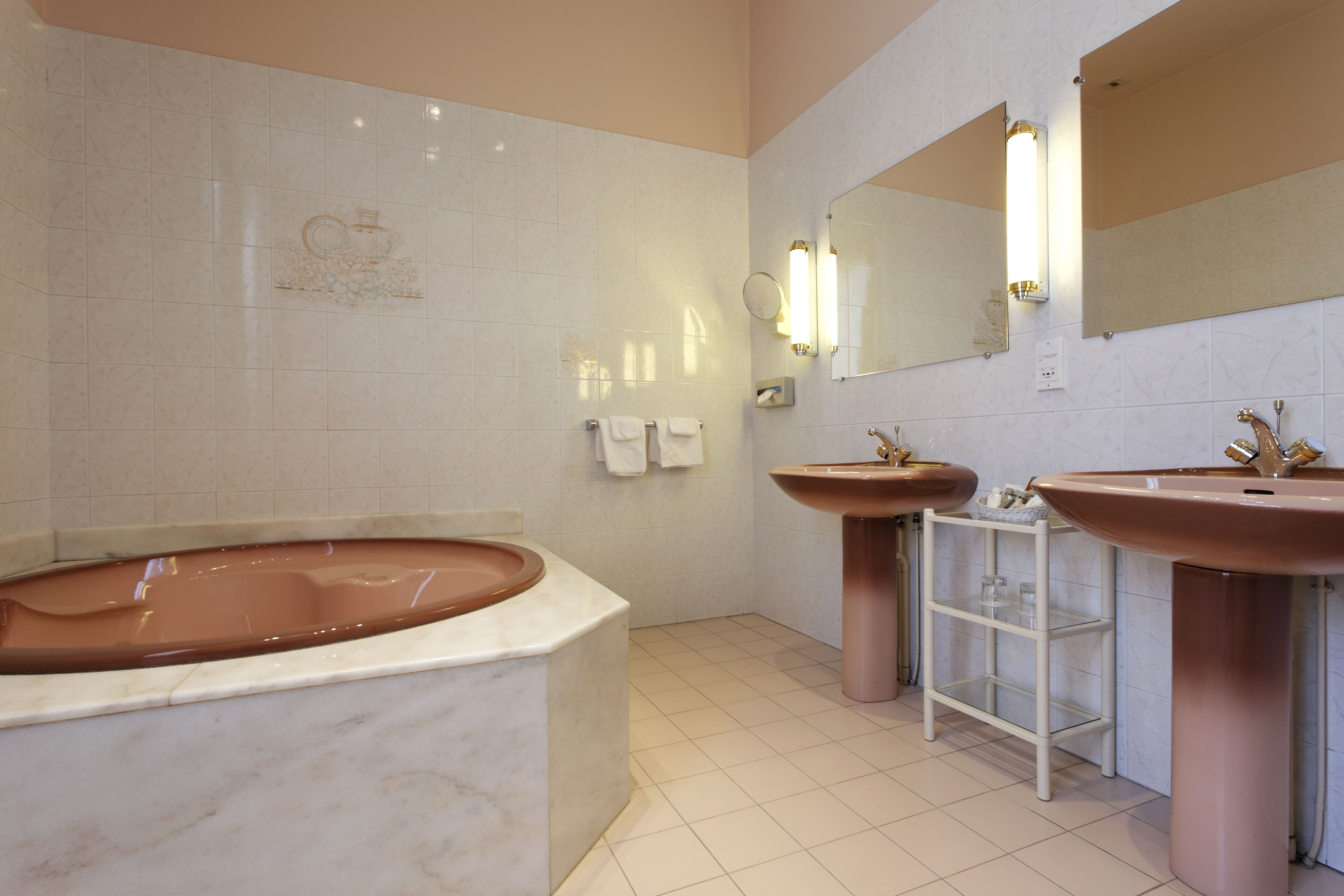 A modern bathroom with a freestanding bathtub, two sinks, and a large mirror.
