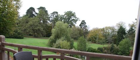Un patio con una mesa y dos sillas, con vista a un jardín con varios árboles y césped.