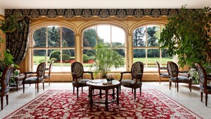 A room with a large window, a red patterned rug, and several chairs. - Château Des Bondons EI (La Ferte-sous-Jouarre)