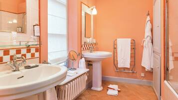 A bathroom with two sinks, a pedestal sink, a mirror, a towel rack, and a shower area.