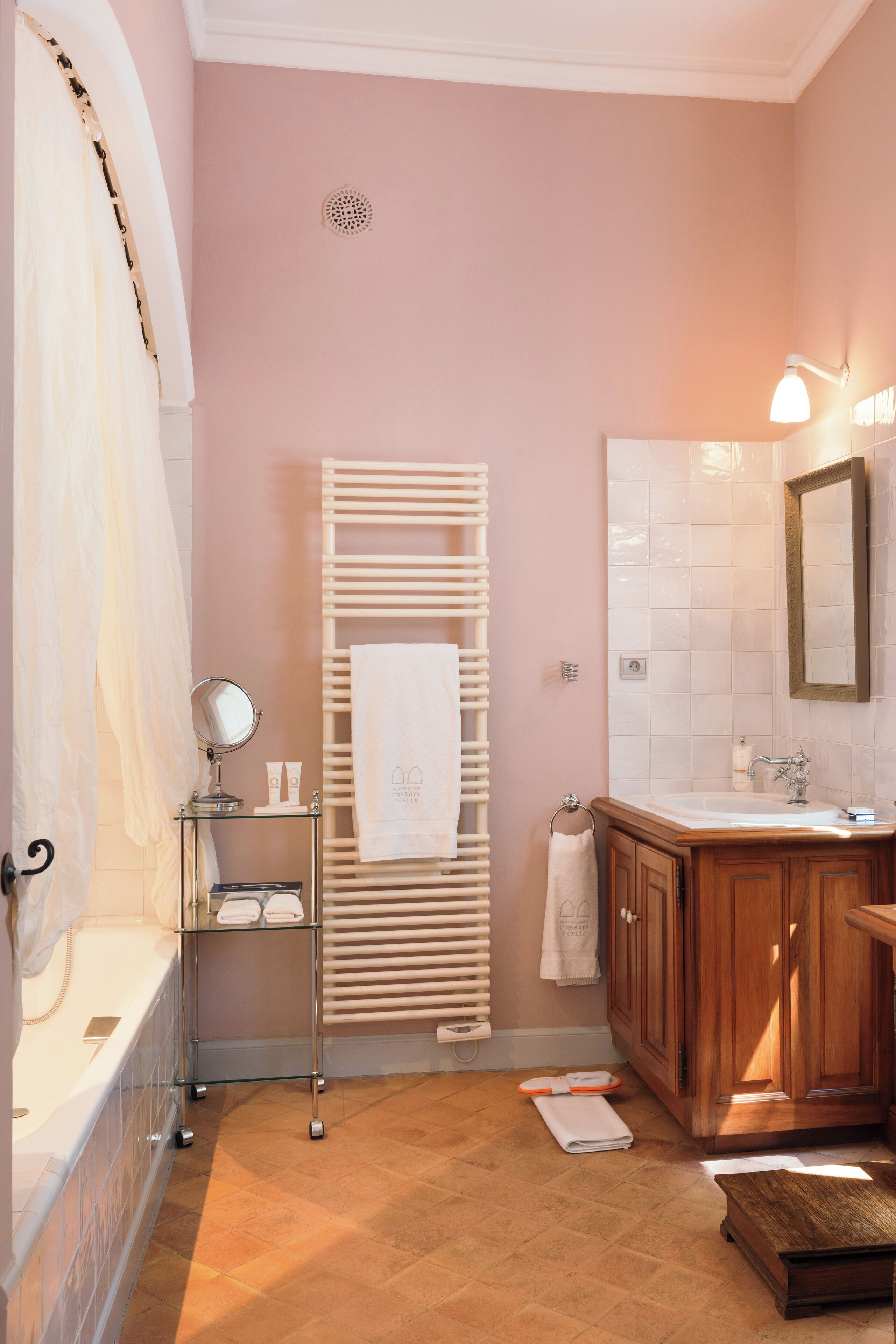 Une salle de bain avec une baignoire, un meuble-lavabo avec un miroir, un porte-serviettes et un rideau de douche.