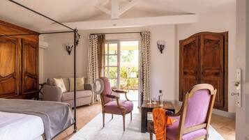 A bedroom with a bed, a chair, a sofa, and a table with a lamp.