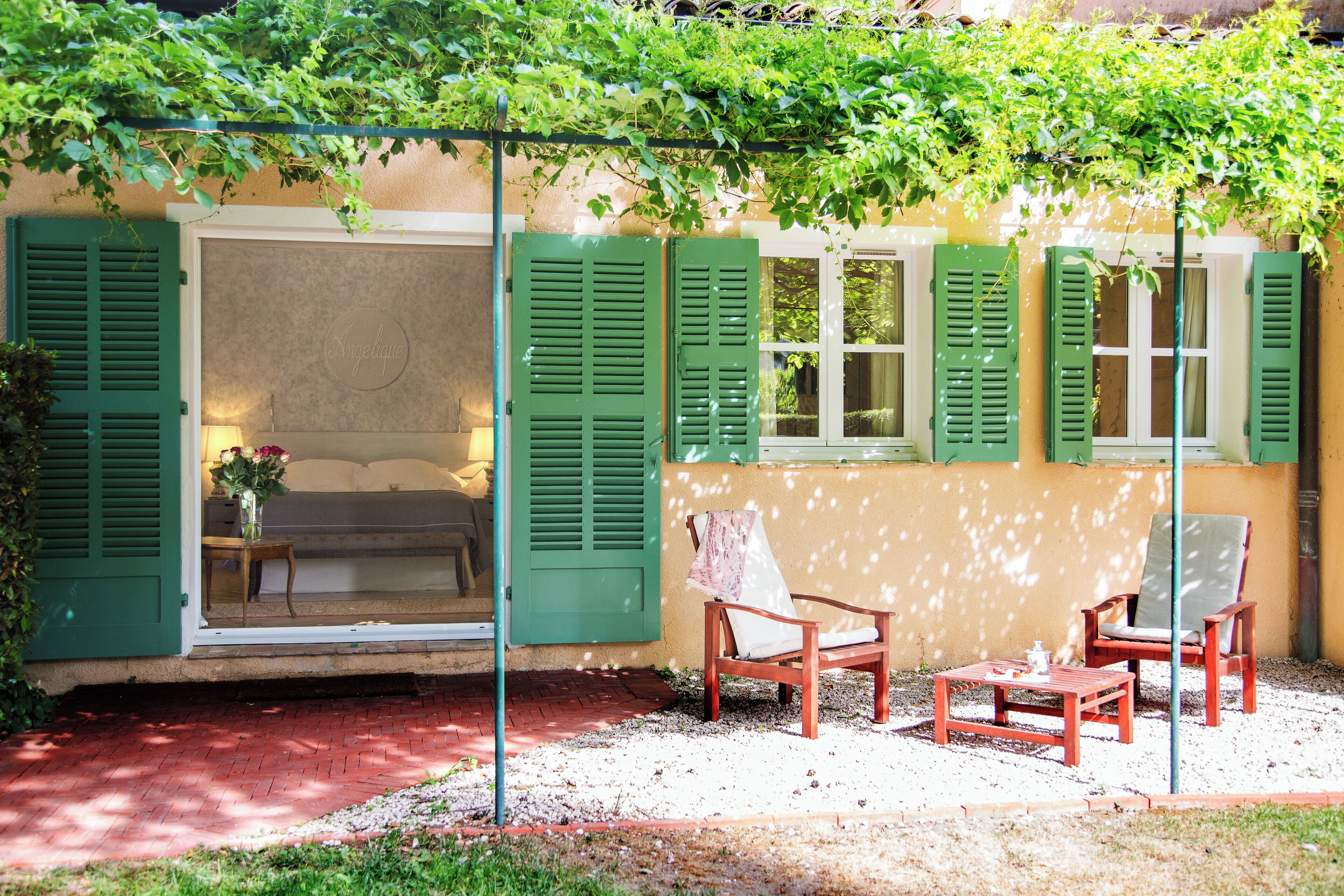 A patio with a wooden bench, two chairs, and a table.