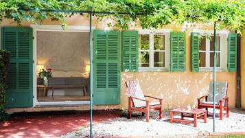 A patio with a wooden bench, two chairs, and a table.